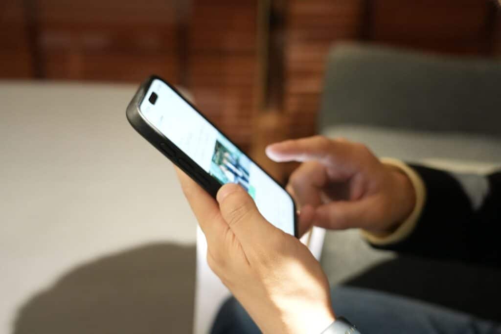 ある人が両手でスマートフォンを持ち、右手の指で画面を操作している