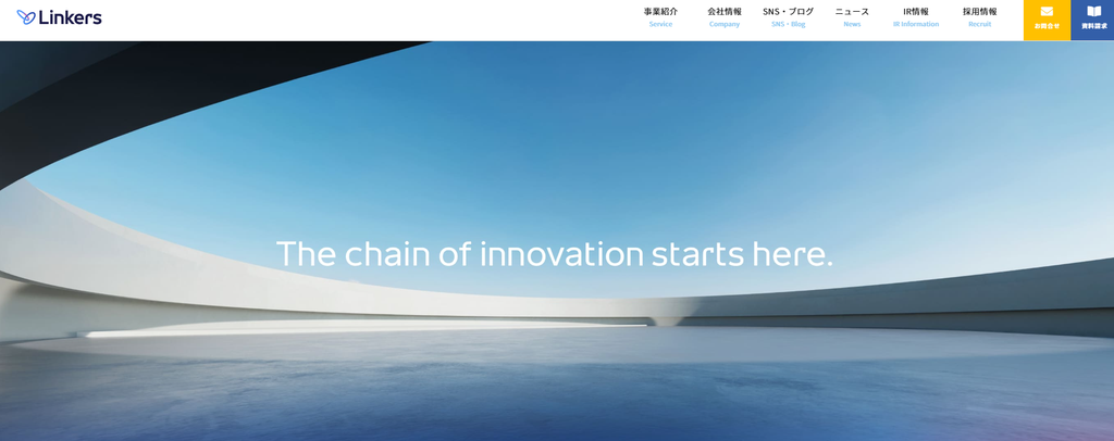 白い曲線の壁と青空。背景の中央には「The chain of innovation starts here」という文字。上部にはロゴとナビゲーションバー